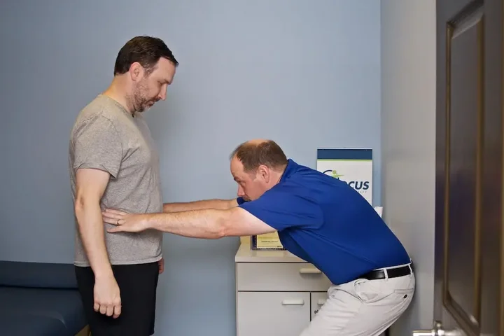 A Doctor of Physical Therapy performing a hands-on assessment with a patient at Focus Physical Therapy